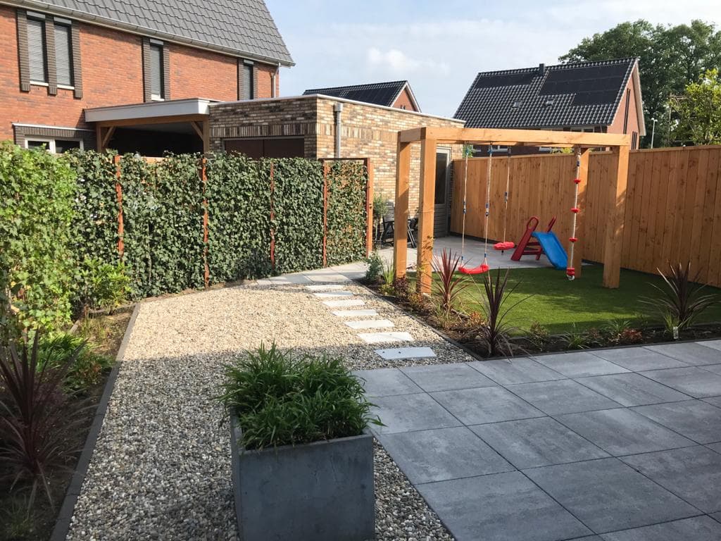 Aangelegde achtertuin met veranda, houten schutting, gazon en sierbestrating