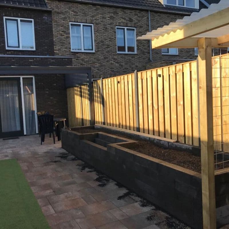 Verlichte houten schutting langs een bestrating achter een woning