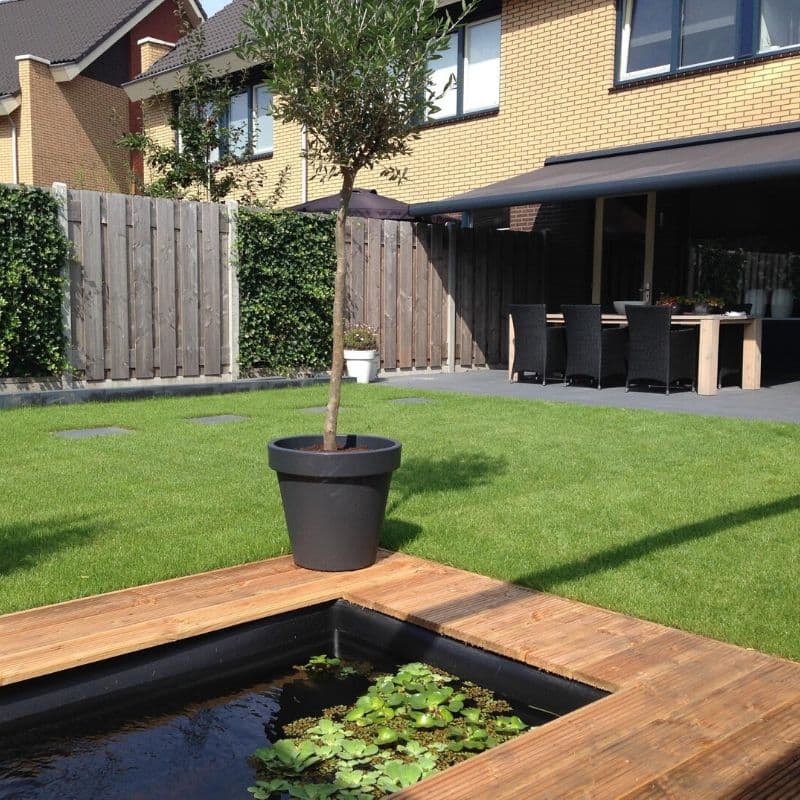 Achtertuin met strak gelegd terras, vijver met houten rand en gazon, aangelegd door H. van den Top in Kootwijkerbroek
