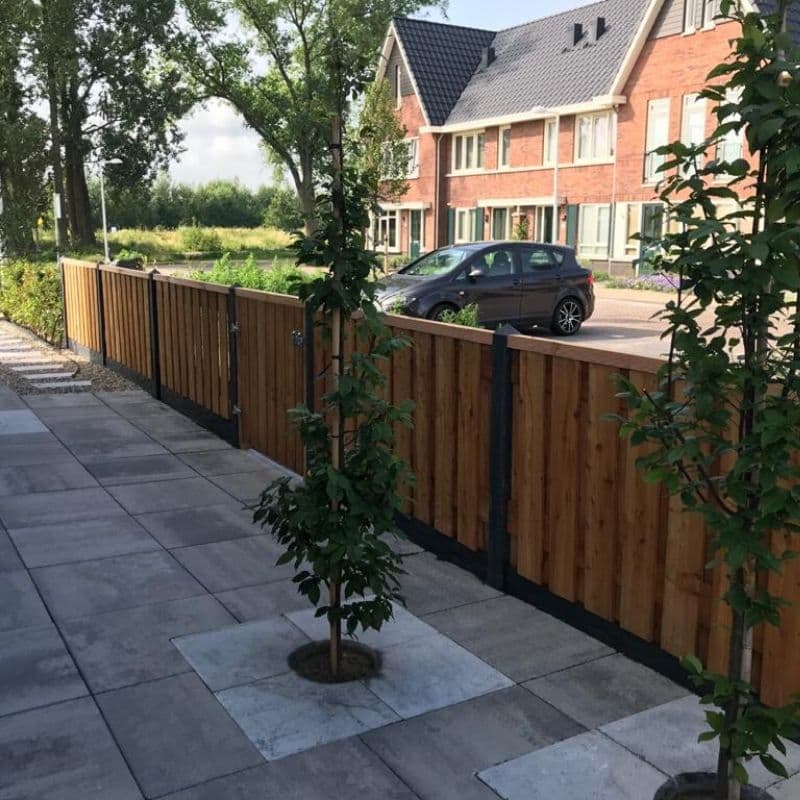 Nieuwe houten schutting en grootformaat tegels langs de oprit van een woning